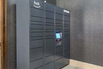 A large group of lockers in a building with a digital screen